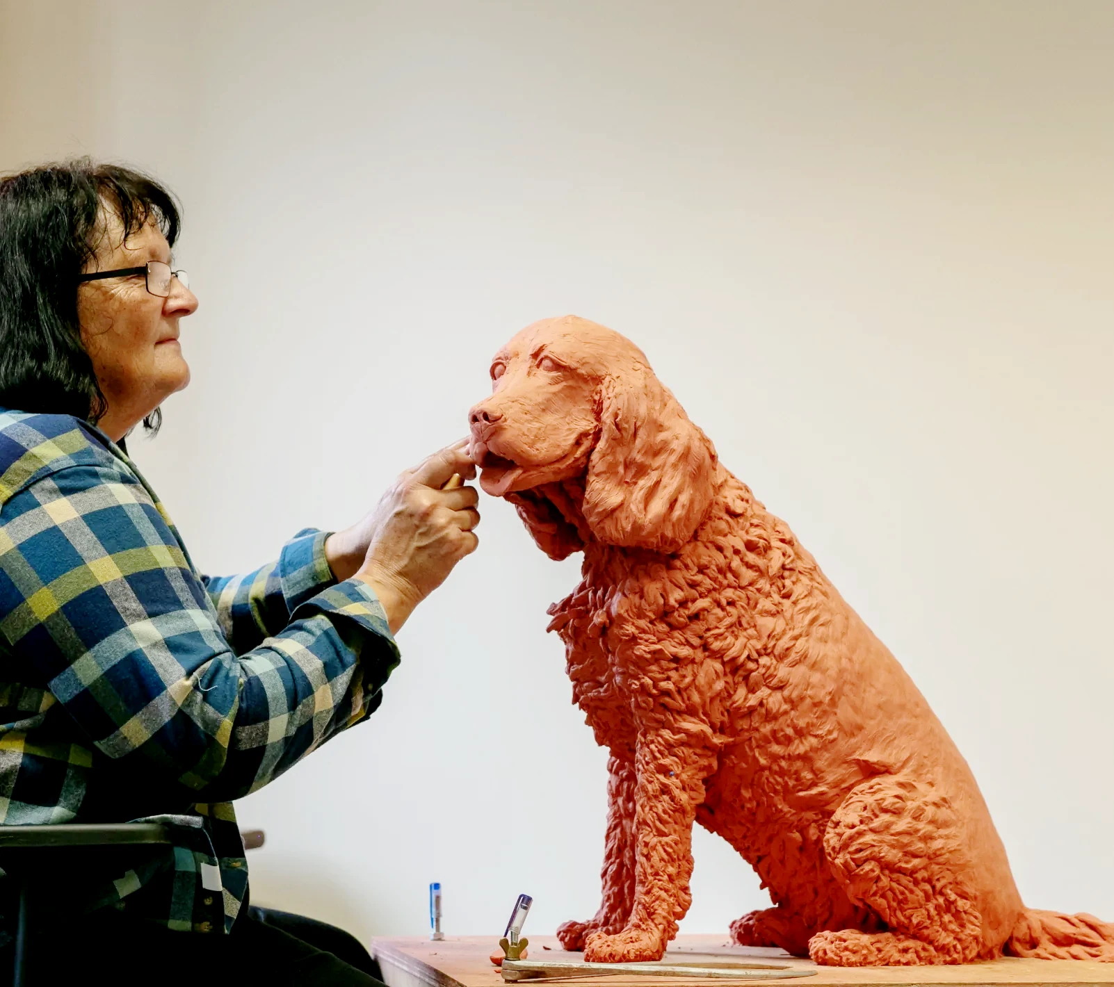 Sculptress Joel with portrait commission in sculpture of a much loved dog. Here in the clay stage Joel builds on the detail