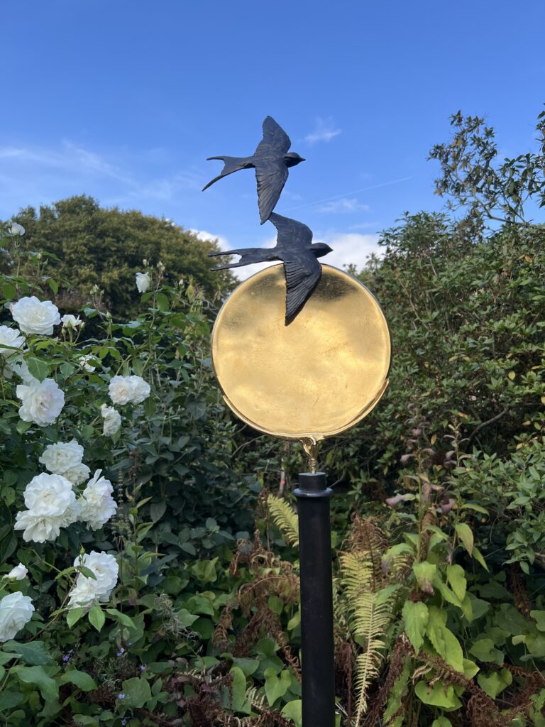 Sun Swallow bronze and golden disc by Joel Walker in the sunshine of a summer garden