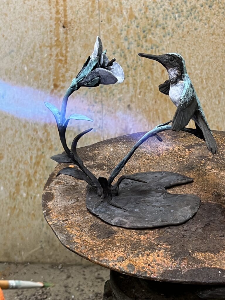 Hummingbird in bronze with flower by Sculptress JOEL during patination some of the greens achieved