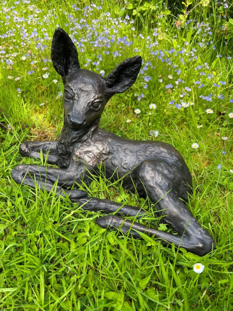 Latest Roe deer fawn bronze lying among the spring flowers
